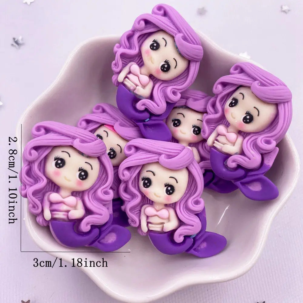A set of purple resin mermaid princess figurines with long hair displayed in a pink dish.