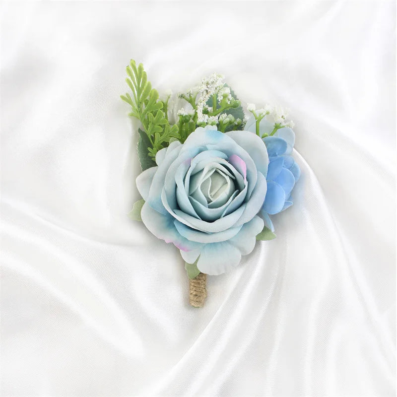 A bouquet of dusty blue silk roses and green foliage arranged as a boutonniere set.