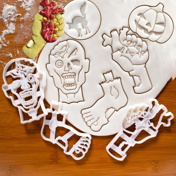 A set of white cookie cutters and fondant stamps shaped like a pumpkin, skull, hand, and other Halloween figures on a wooden 