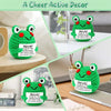 A green crochet frog ornament with a happy expression displayed on a white surface.