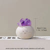 A small, smooth white bean-shaped decorative stone topped with a purple amethyst crystal.