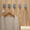 A display of five self-adhesive wall hooks and a hanger with a beige knitted sweater and a cream handbag.