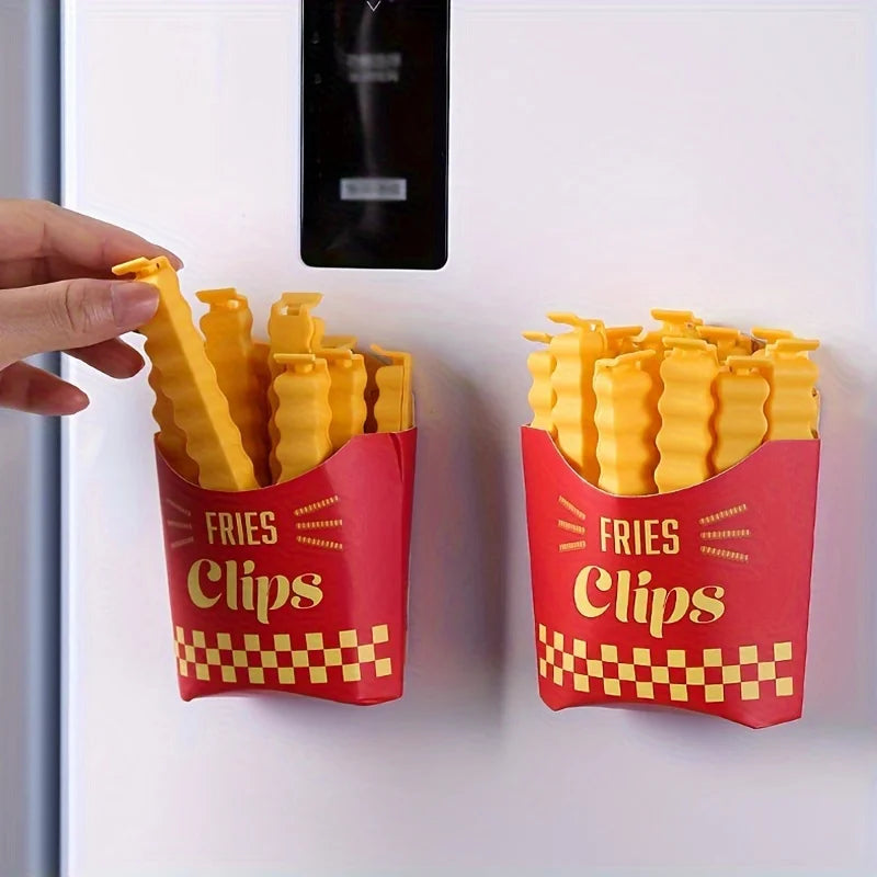 A hand is holding a red container of yellow French fry shaped sealing clips on a white surface.