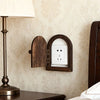 A close-up of a decorative wooden outlet cover mounted on a wall next to a lamp.