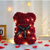Roter künstlicher Rosen-Teddybär, beleuchtet mit warmen Lichtern, liegt auf einer weißen Oberfläche.
