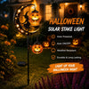 A solar stake light featuring a crescent moon and black cat design illuminating a Halloween night.
