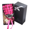 A black gift box containing a bouquet of pink roses tied with a white ribbon and a pink bow.