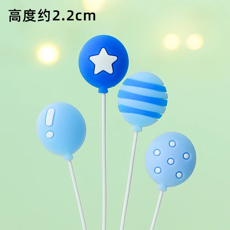 A set of three blue balloon cake toppers featuring a star, stripes, and polka dots on white sticks.