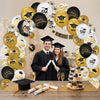 A collection of black and gold graduation balloons with cap and star designs arranged on a wooden surface.