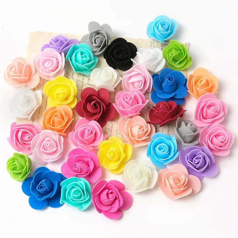 Colección de decoraciones de espuma de rosa artificial en varios tonos de rosa, azul, verde y naranja, dispuestas sobre una t