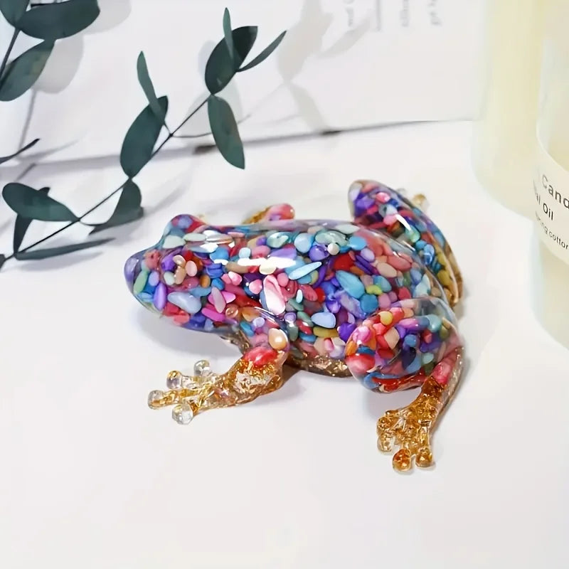 A vibrant, iridescent crystal frog resin craft decoration resting on a white surface.