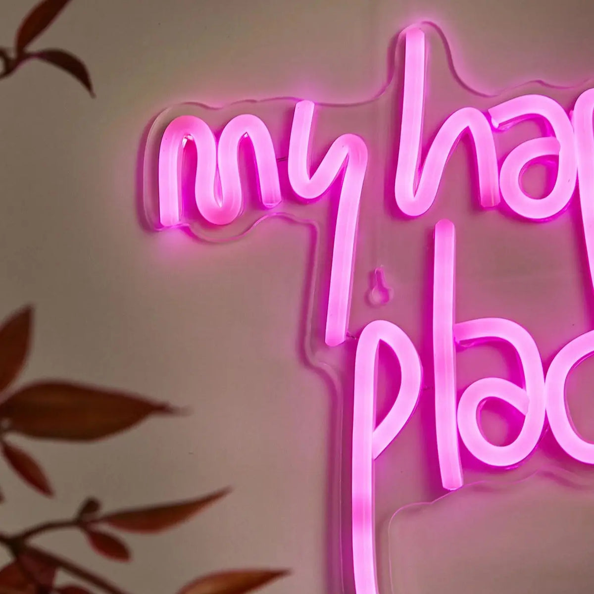 Pink neon sign spelling out My Happy Place on a clear acrylic background.
