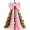 A Christmas tree decorated with red ornaments and a large pink velvet bow with long streamers.
