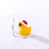 A yellow glow-in-the-dark Christmas duck figurine wearing a red and white Santa hat, photographed on white snow.