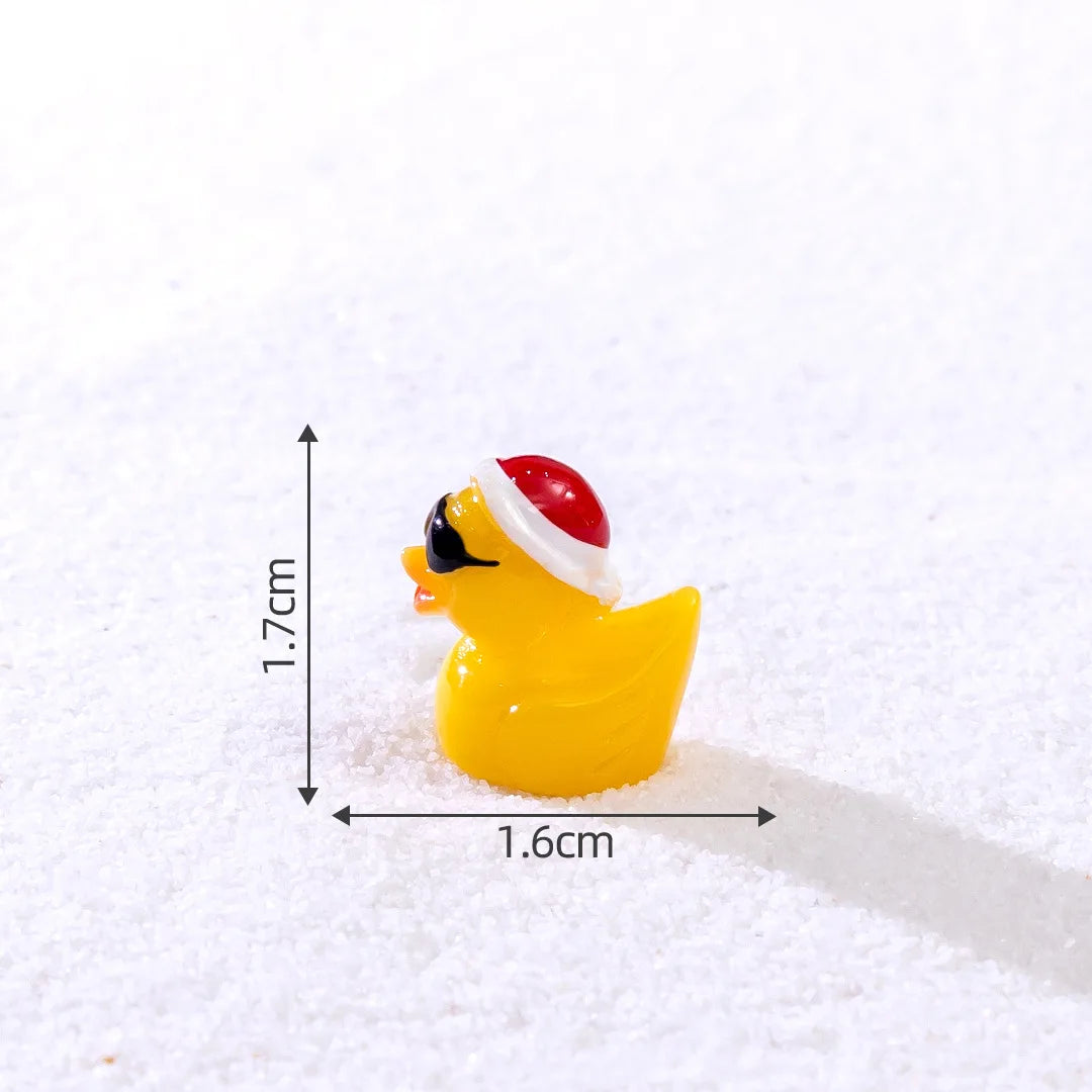 A yellow glow-in-the-dark Christmas duck figurine wearing a red and white Santa hat, photographed on white snow.
