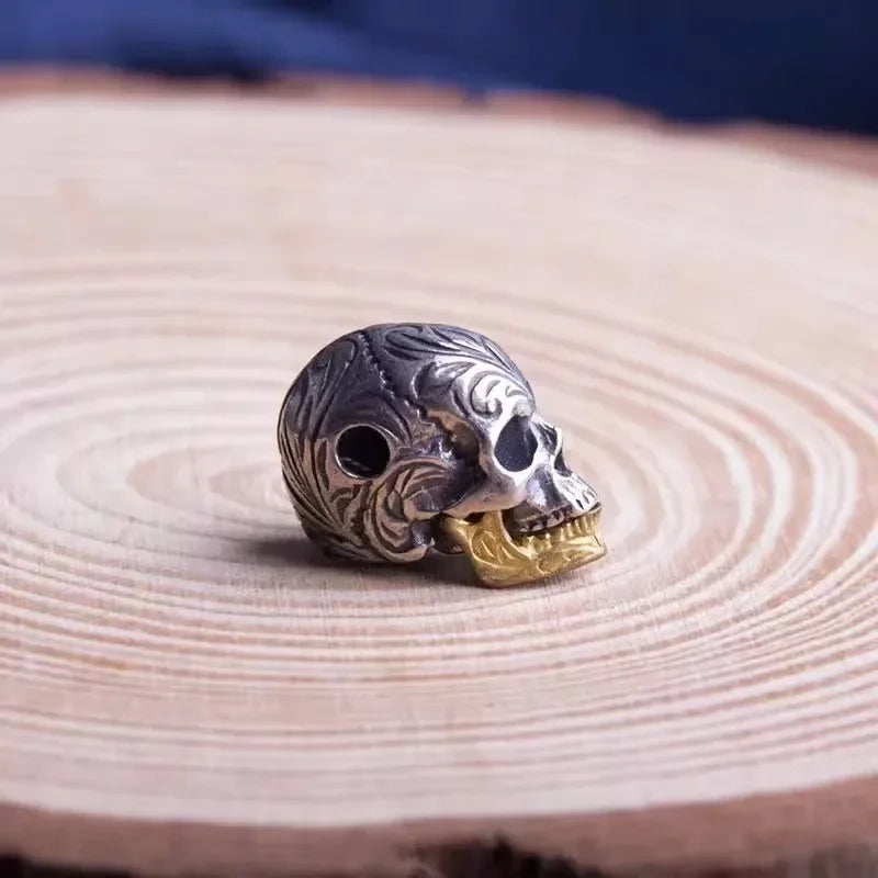 A silver skull bead pendant necklace resting on a light wooden surface.