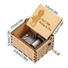 A vintage hand-cranked wooden music box with a lid featuring a silhouette of a couple and decorative wood grain.