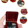 A close-up view of a red music box with an open lid, showing the internal mechanism and decorative elements.