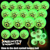 A hand holds a cluster of bright green glow-in-the-dark eyeball bouncy balls against a dark background.