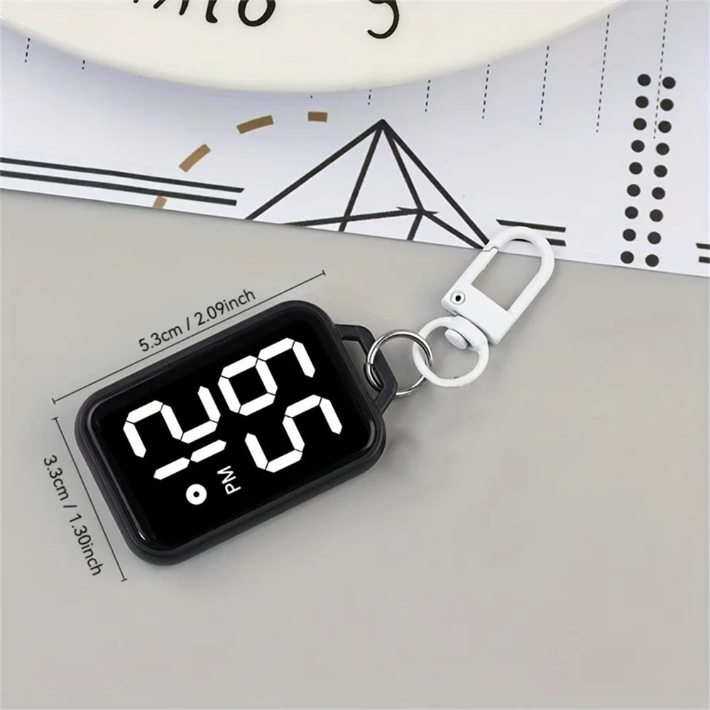 A black LED keychain pocket watch with a digital display showing 2:09 PM on a gray surface.