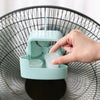 A hand is placing an ice cube into the compartment of a teal portable ice-cooling floor fan.