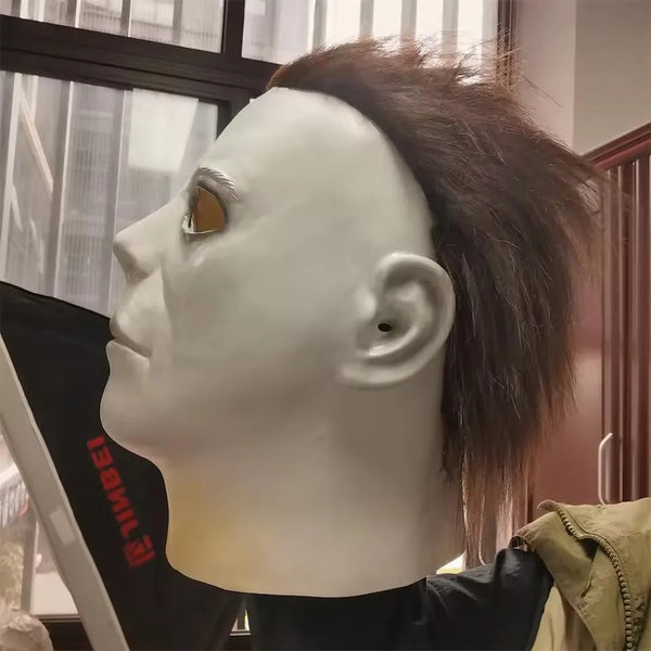 A white latex mask shaped like a human head is displayed against a blurred background.