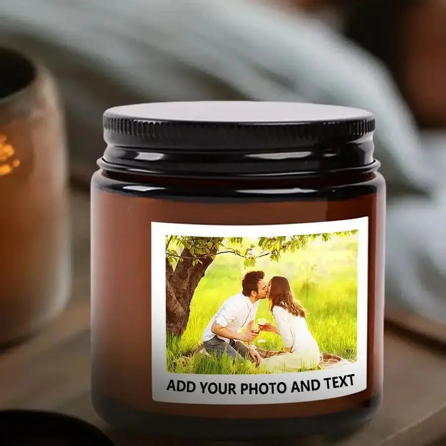 A dark brown jar candle with a black lid, featuring a photo of a couple embracing in a sunny outdoor setting.