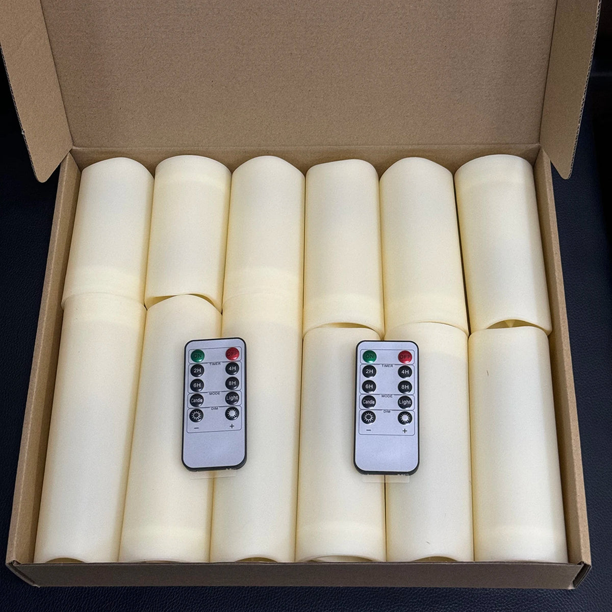 A cardboard box containing four white flameless LED candles with remote controls.