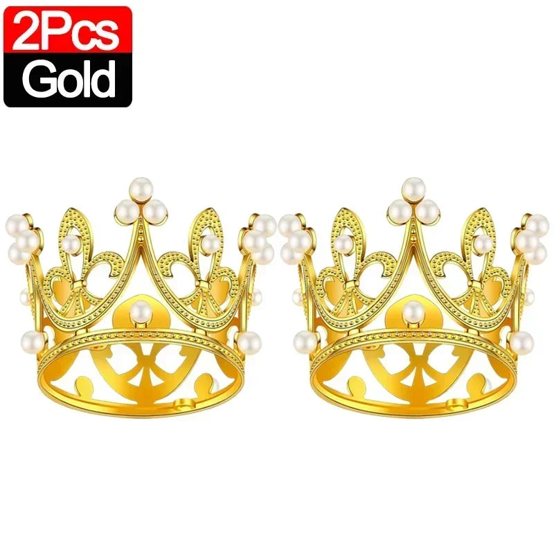 A pair of gold crown cake toppers with pearl accents.