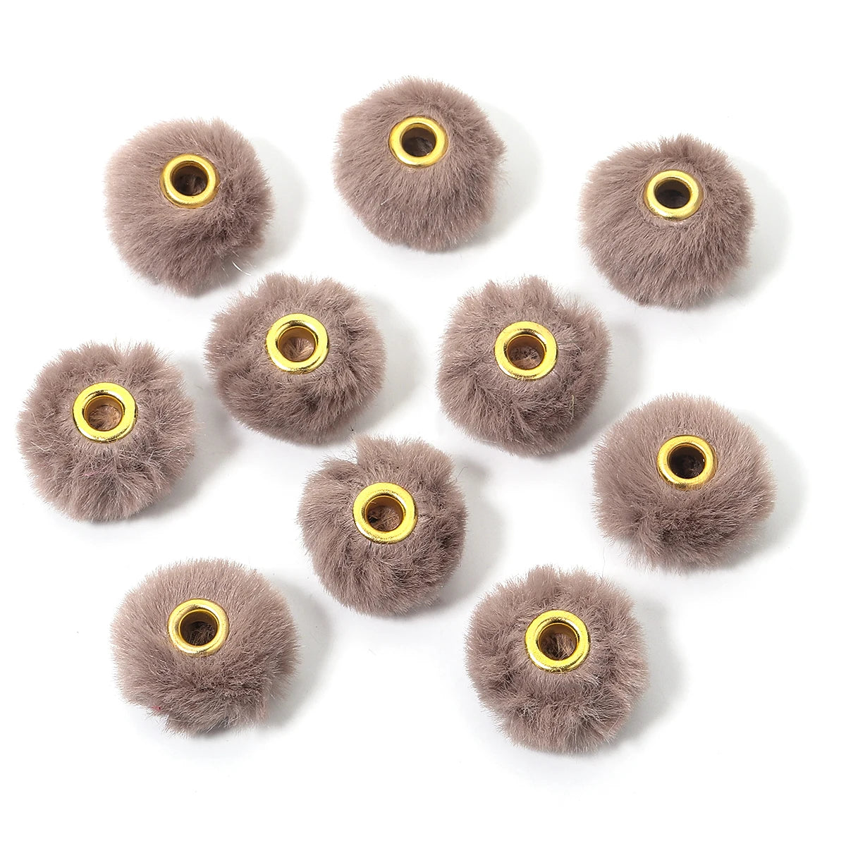 Collection de petites boules de fourrure grise et duveteuse utilisées comme perles pour la création de bijoux DIY.