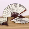 A retro folding fan with a dark wood frame and light green and black bamboo leaf patterns.