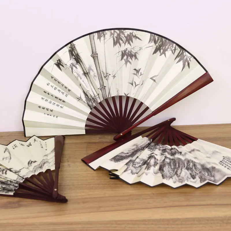 A retro folding fan with a dark wood frame and light green and black bamboo leaf patterns.