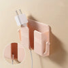 A pink wall-mounted organizer with a phone holder and charging dock is shown against a beige wall.