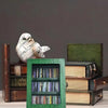 A decorative book display featuring a white bird figurine and stacked books in dark wood and green accents.