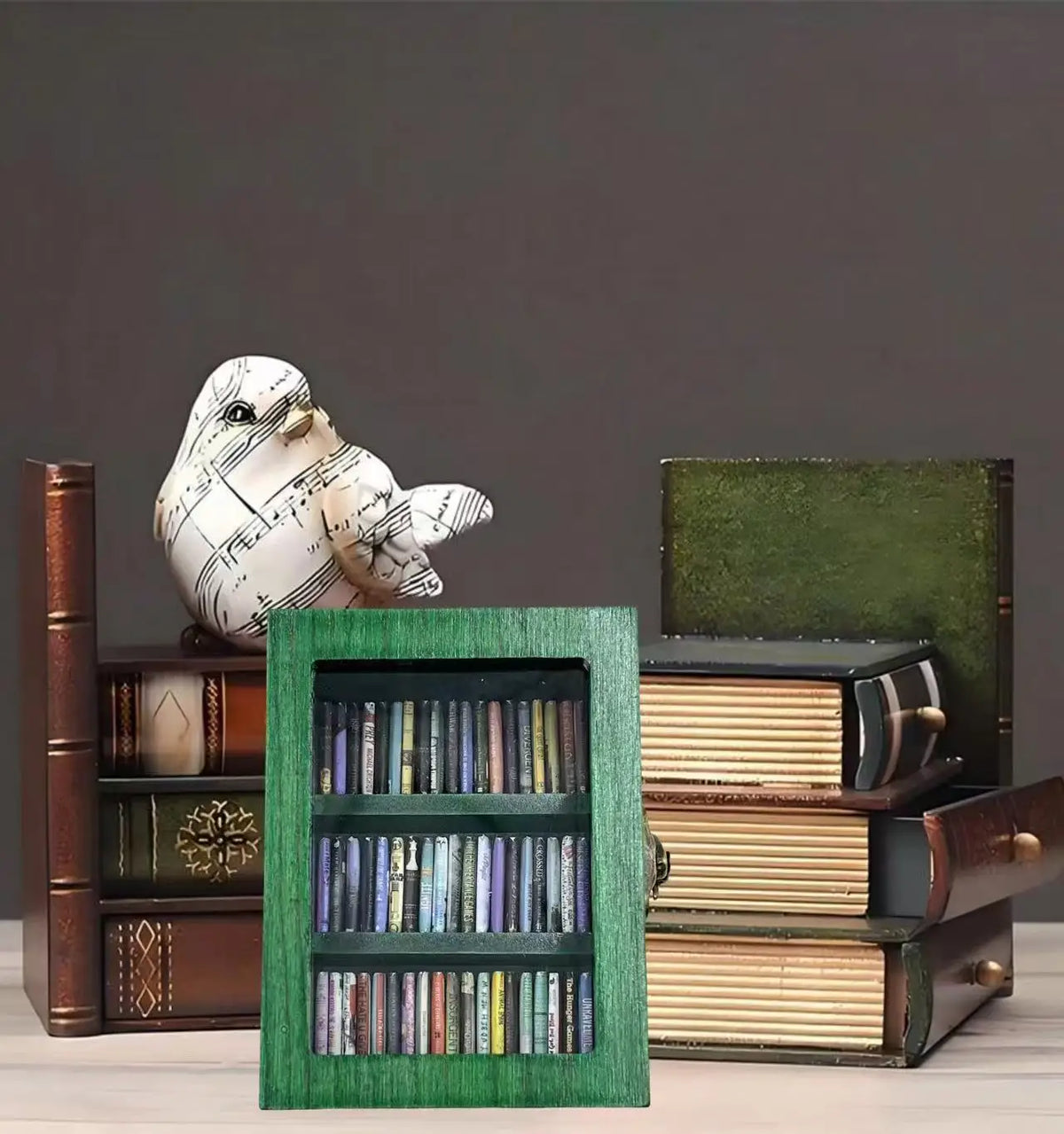 A decorative book display featuring a white bird figurine and stacked books in dark wood and green accents.