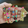 A hand holds a rosary necklace featuring various colored beads and a gold Santa Muerte figure.