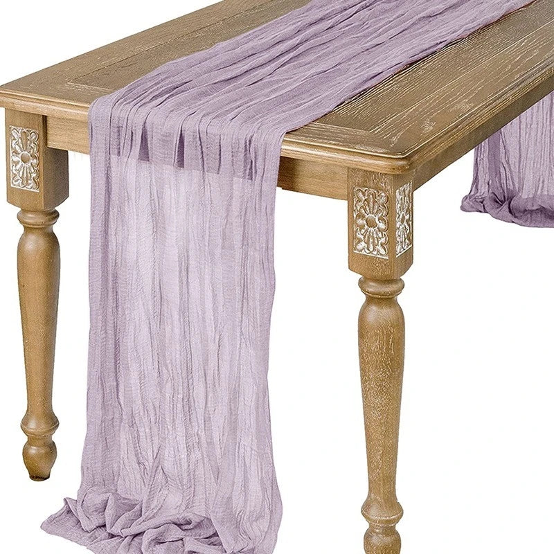 A purple semi-sheer gauze table runner draped over a wooden table.