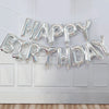 A silver foil letter balloon banner spelling out Happy Birthday across a white door.