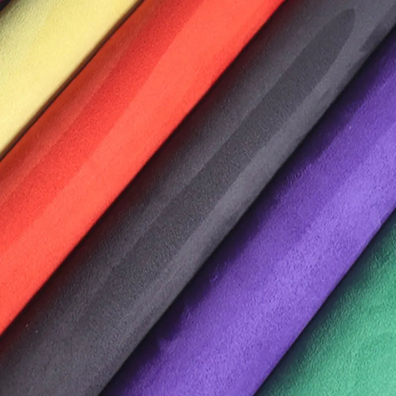 A close-up of several rolls of self-adhesive suede wrap fabric in various colors including yellow, orange, gray, and purple.