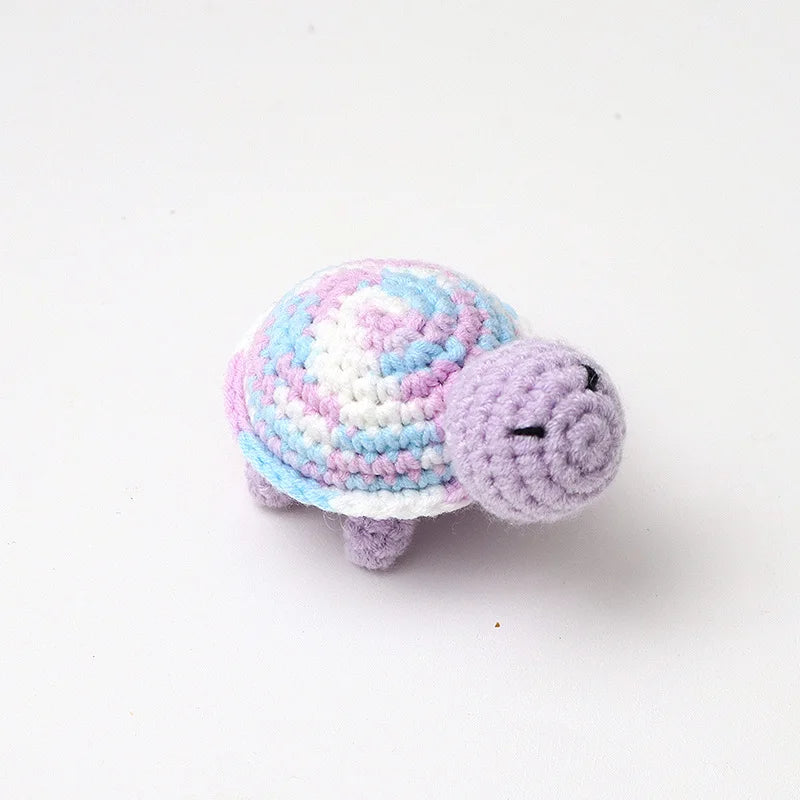 Handmade crocheted turtle plush with pink and blue scales and a purple head