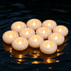 A cluster of floating white LED candles casting a warm glow on dark water.
