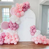 A display of pink and white pastel latex balloons arranged in a balloon arch shape.