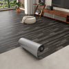 Roll of 3D textured wood grain self-adhesive flooring film displayed on a light floor.