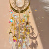 Gold star moon wind chime featuring a crescent moon and sun with dangling clear and iridescent crystals