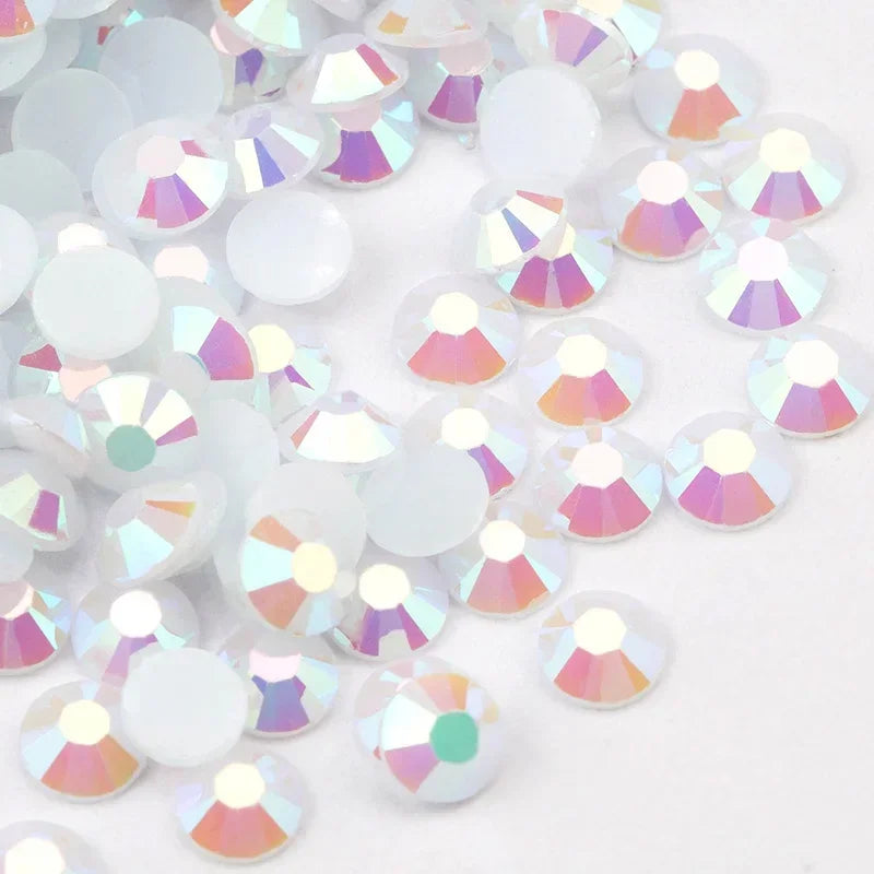 A close-up view of round flatback resin rhinestones in various iridescent colors scattered on a white surface.
