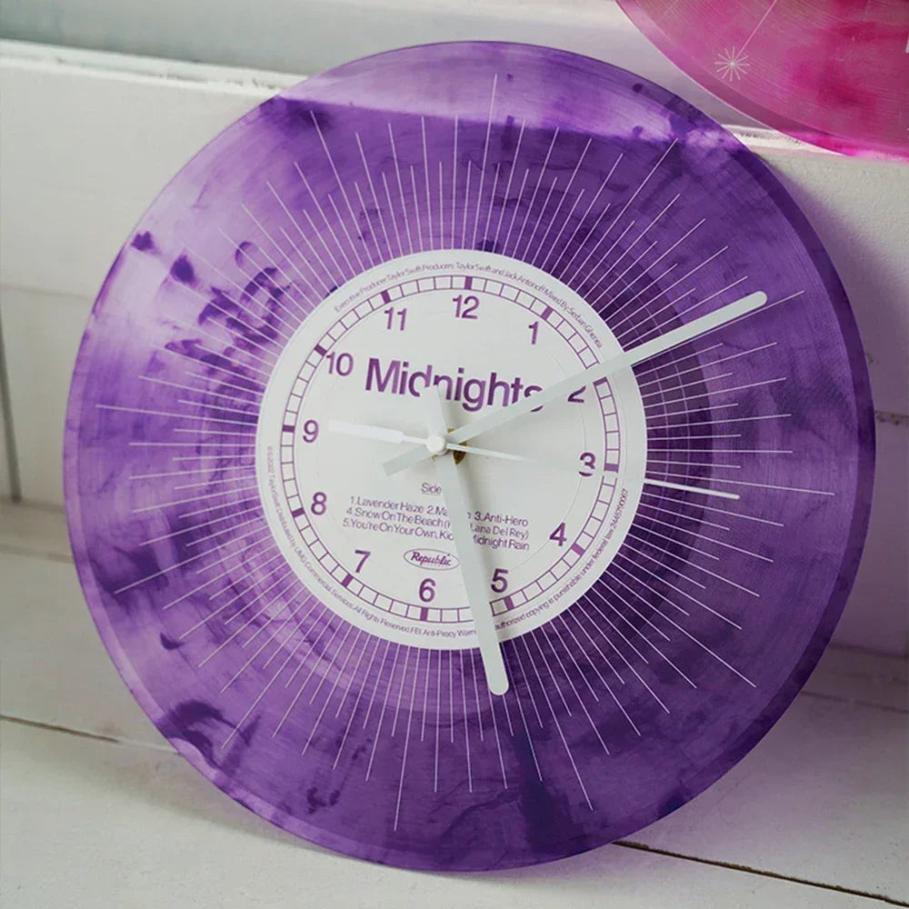 A purple vinyl record wall clock with a transparent cover and white face displaying midnight.