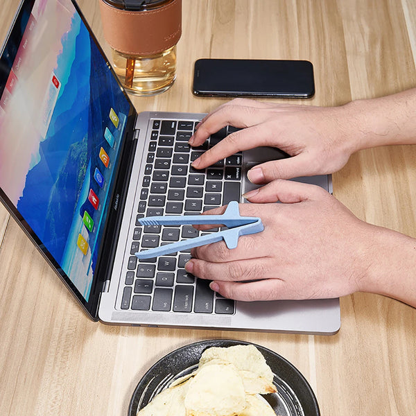 A person uses reusable blue wheat straw chopsticks to pick up food while using a laptop.