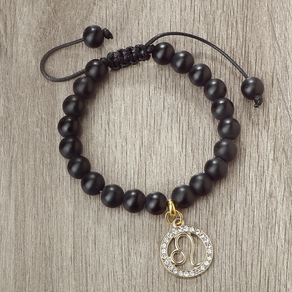 A handmade beaded bracelet featuring natural black stones and a gold zodiac charm.