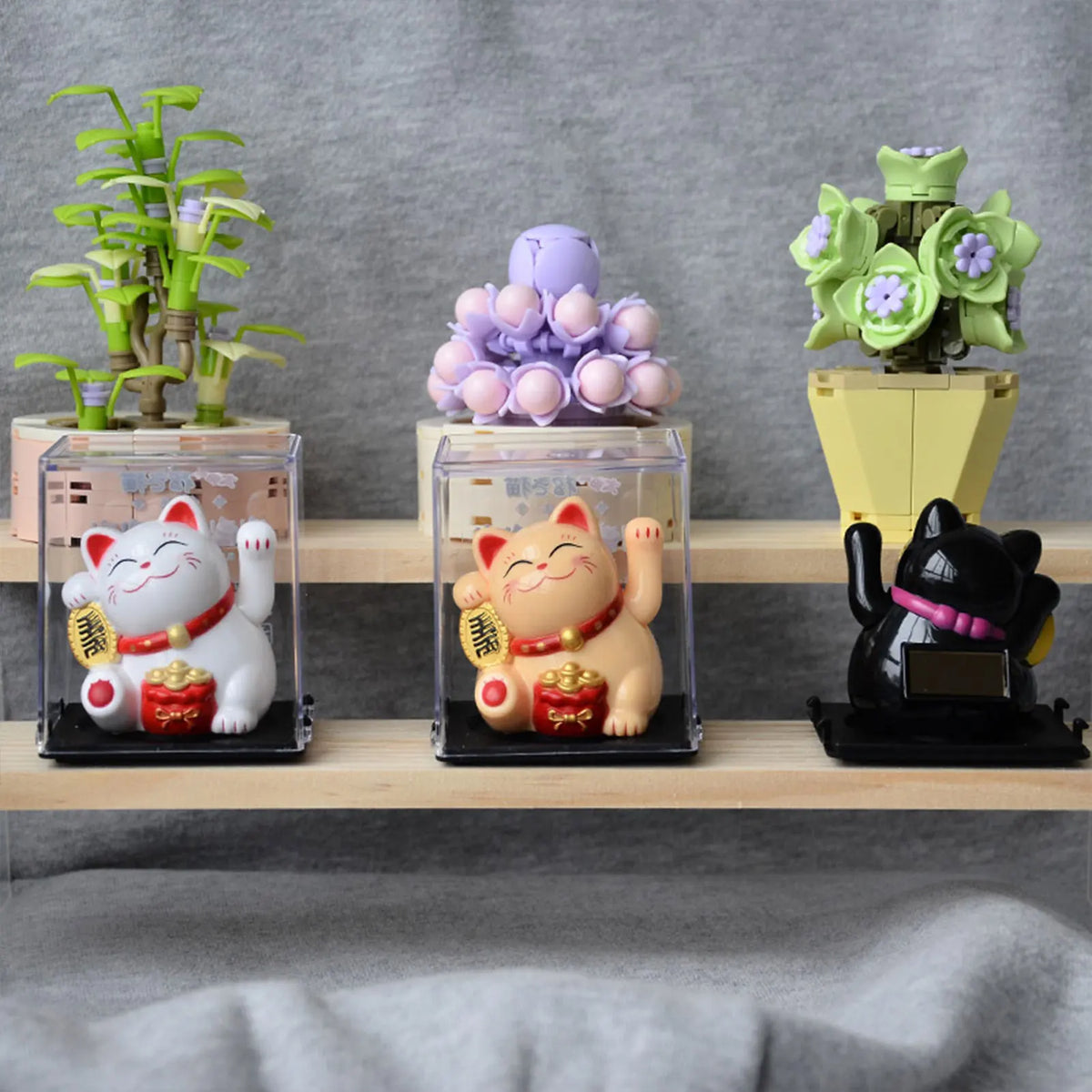 A display of solar-powered waving lucky cat figurines in various colors and sizes on a wooden shelf.