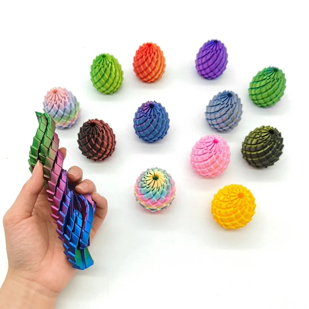 A hand holds a variety of colorful, textured 3D printed dragon egg fidget toys scattered on a white surface.
